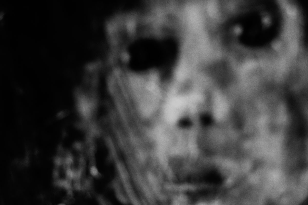 A blurred, grainy face, the eyes like two holes.