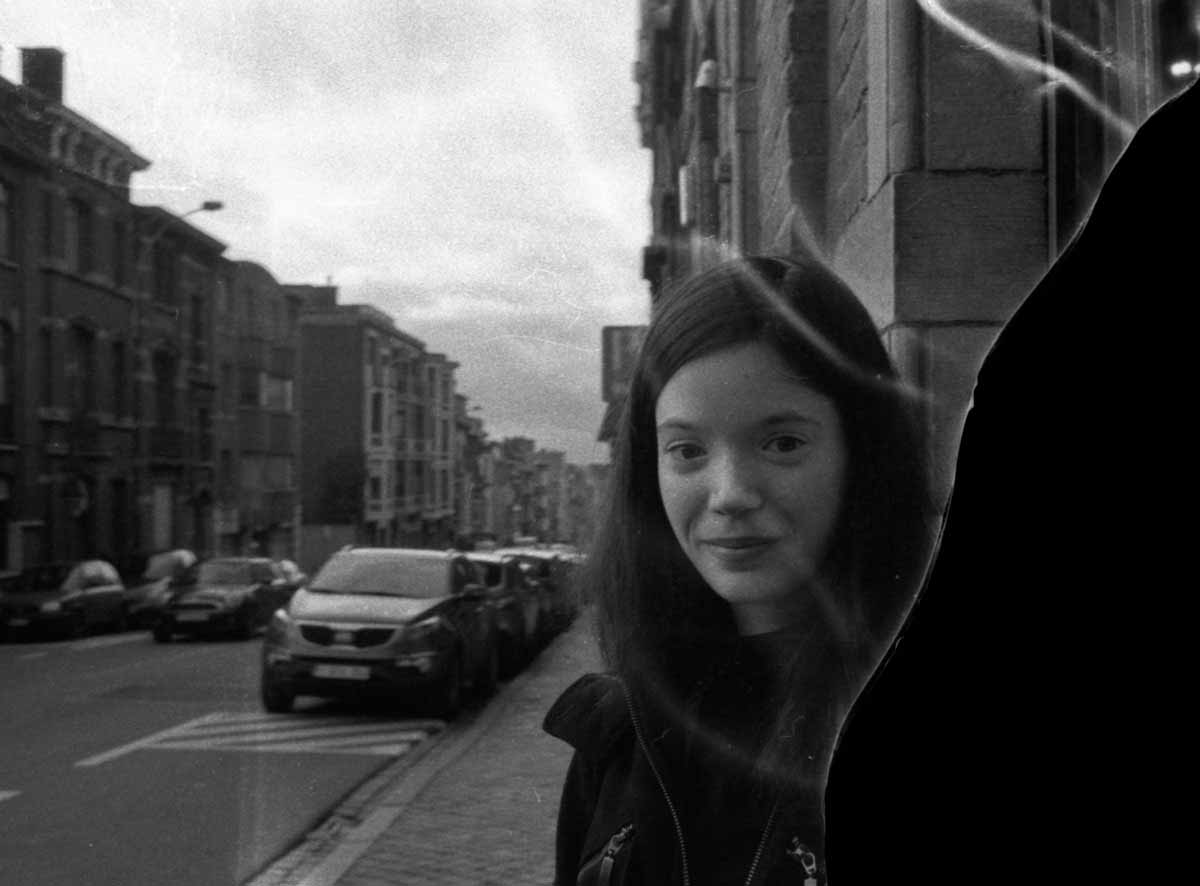 Portrait of a young woman smiling in a street, the image torn at the side.