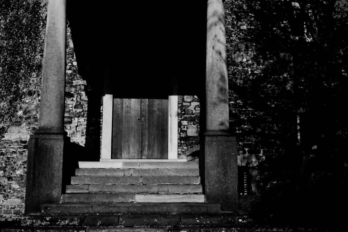A columned portico, stone steps and a closed wooden door.